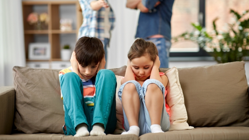 Decorative image of two children placing their hands over their ears to block the sound of their parents arguing.