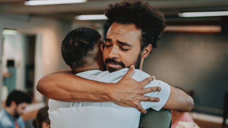 Decorative image of two men hugging and giving each other the support they need