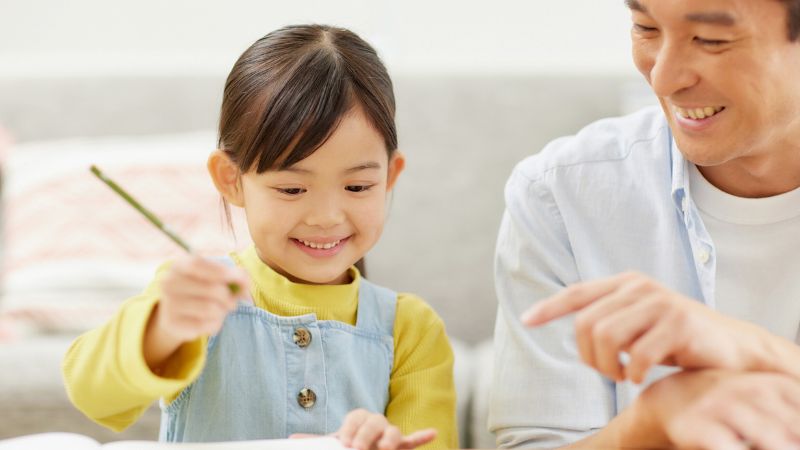 Decorative image of a father encouraging his daughter as she draws a picture