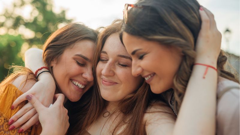 Decorative image of a woman with a good support system, embracing her two friends.