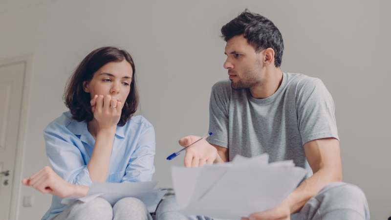 Decorative image of parents deep in a discussion with each other. The father is gesturing at some documents while the mother gazes at the content, worry in her expression