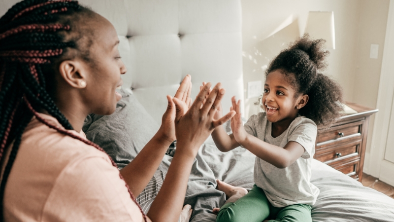 Decorative image of a child high-fiving their parent